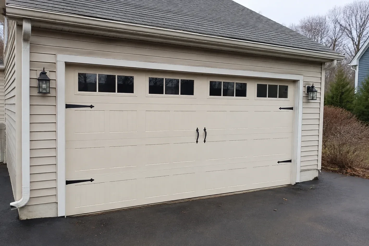 Cream carriage-house-style garage door with dark decorative hardware. — Carriage-House Garage Door Installation, Kawartha Lakes